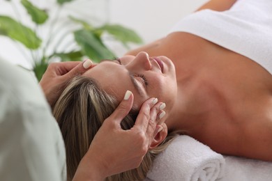 Photo of Beautiful woman receiving facial massage indoors, closeup