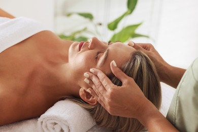 Photo of Beautiful woman receiving facial massage indoors, closeup