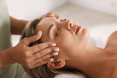 Photo of Beautiful woman receiving facial massage indoors, closeup