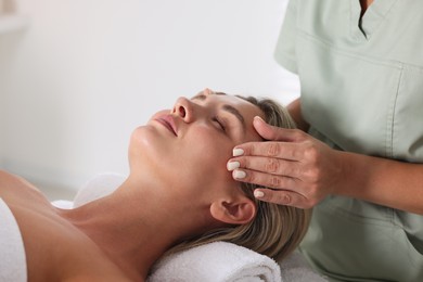 Photo of Beautiful woman receiving facial massage indoors, closeup