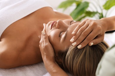 Photo of Beautiful woman receiving facial massage indoors, closeup
