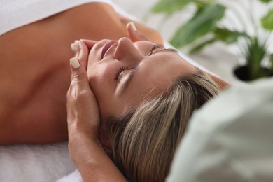Photo of Beautiful woman receiving facial massage indoors, closeup