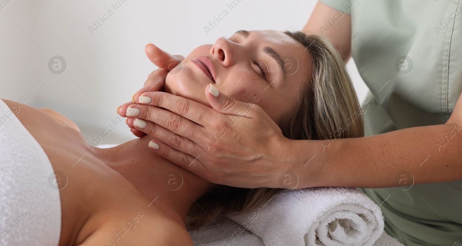 Beautiful woman receiving facial massage on couch indoors, closeup Photo of Beautiful woman receiving facial massage on couch indoors, closeup