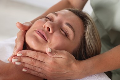 Photo of Beautiful woman receiving facial massage indoors, closeup