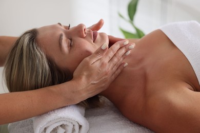 Photo of Beautiful woman receiving facial massage on couch indoors, closeup