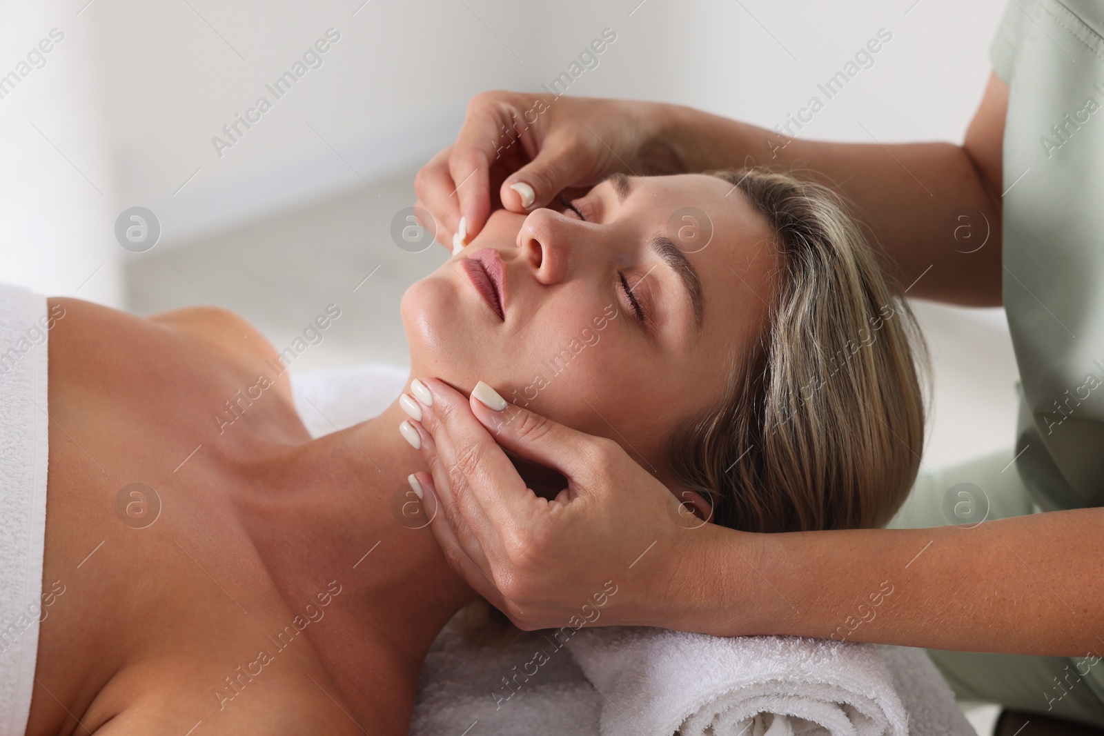 Beautiful woman receiving facial massage on couch indoors, closeup Photo of Beautiful woman receiving facial massage on couch indoors, closeup
