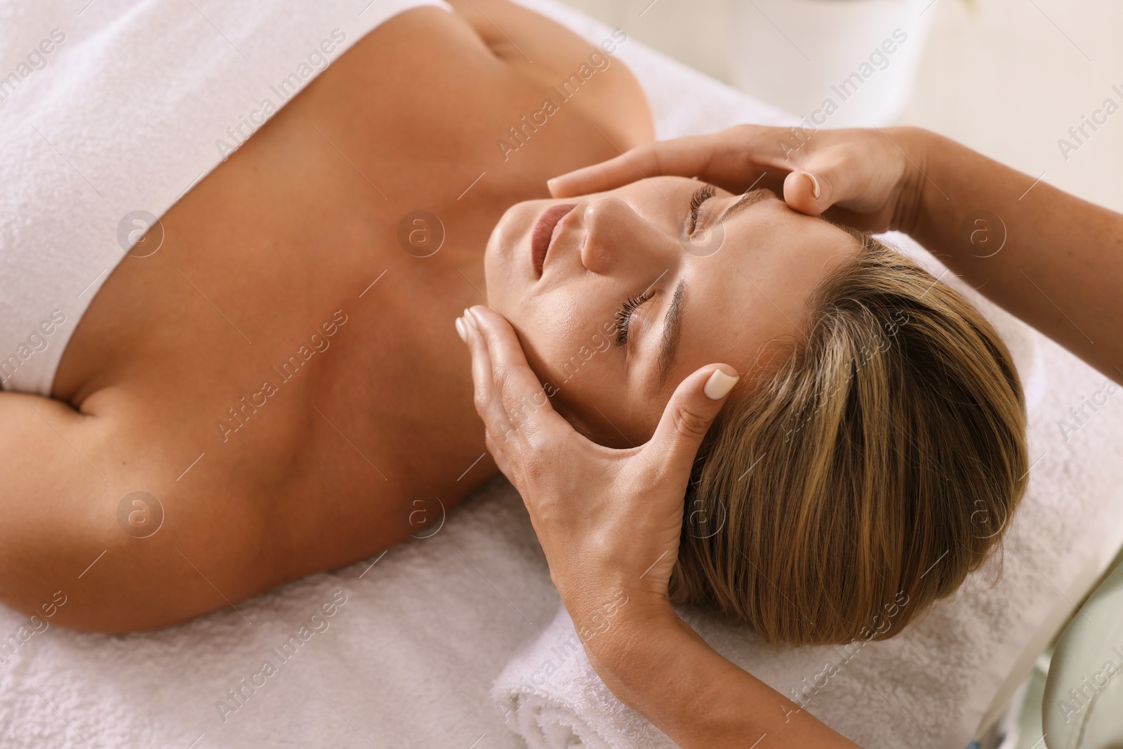 Beautiful woman receiving facial massage on couch indoors, closeup Photo of Beautiful woman receiving facial massage on couch indoors, closeup