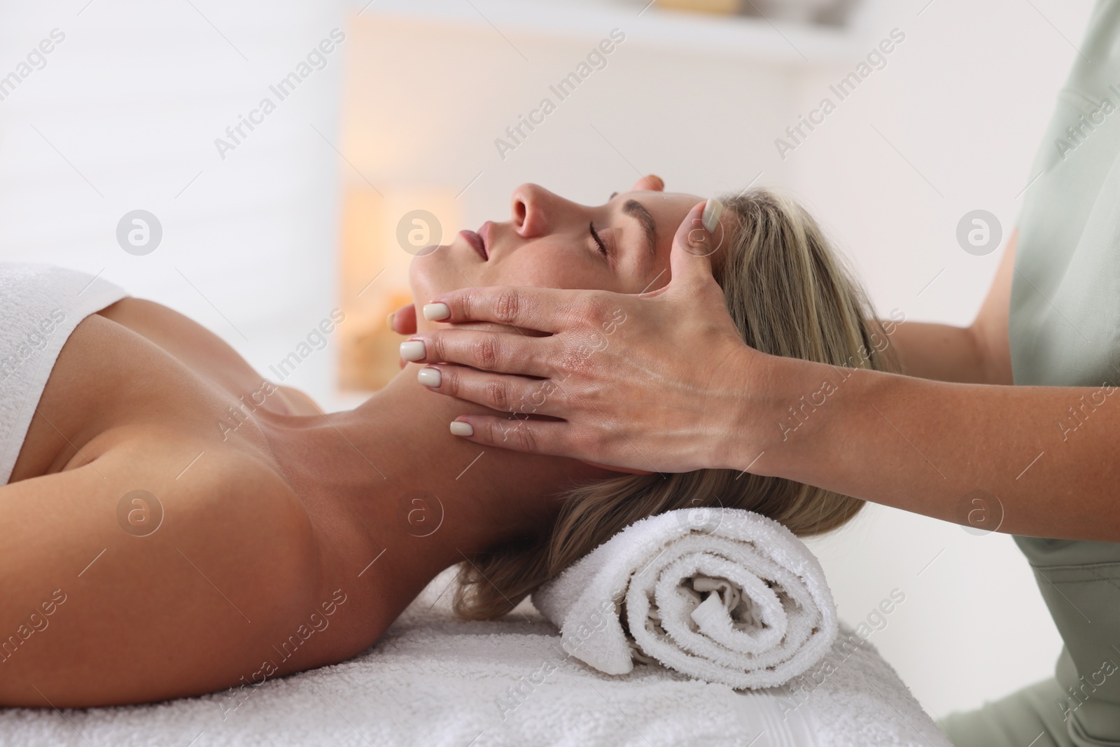 Beautiful woman receiving facial massage on couch indoors, closeup Photo of Beautiful woman receiving facial massage on couch indoors, closeup
