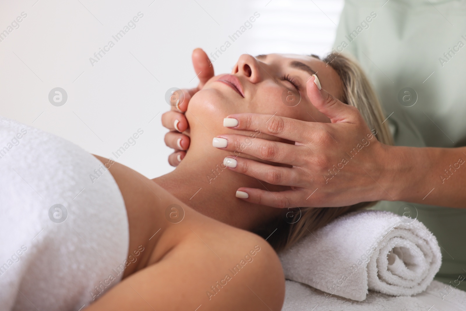 Beautiful woman receiving facial massage on couch indoors, closeup Photo of Beautiful woman receiving facial massage on couch indoors, closeup