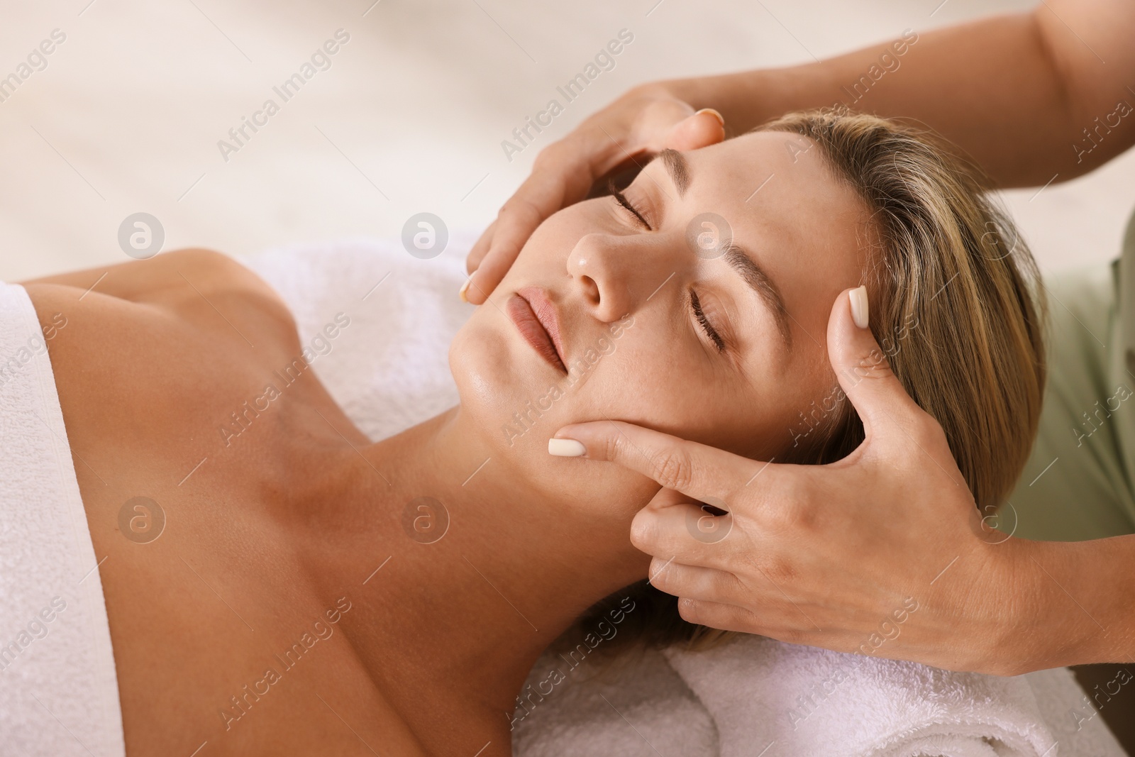 Beautiful woman receiving facial massage on couch indoors, closeup Photo of Beautiful woman receiving facial massage on couch indoors, closeup