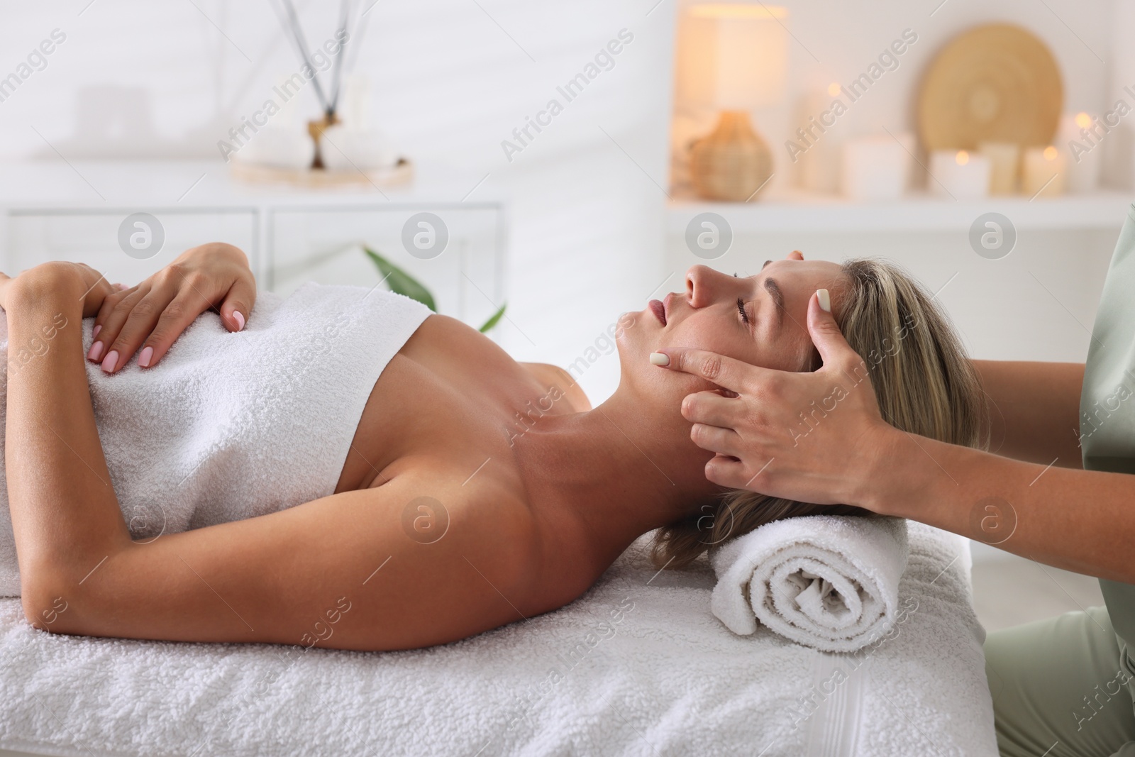 Beautiful woman receiving facial massage on couch in spa salon, closeup Photo of Beautiful woman receiving facial massage on couch in spa salon, closeup