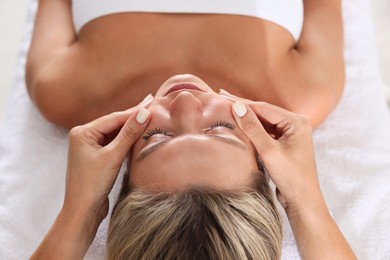 Photo of Beautiful woman receiving facial massage on couch, closeup