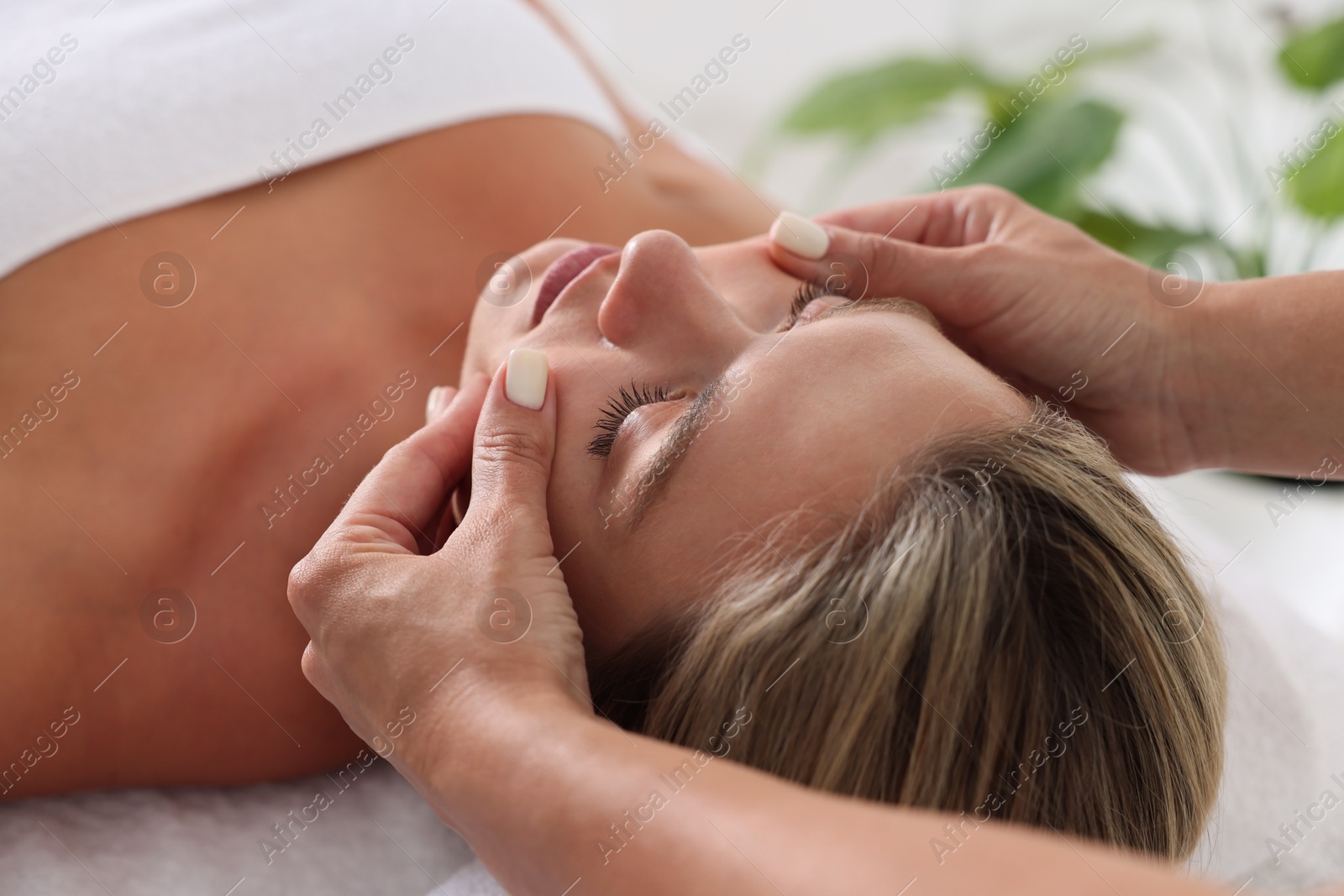 Beautiful woman receiving facial massage on couch indoors, closeup Photo of Beautiful woman receiving facial massage on couch indoors, closeup