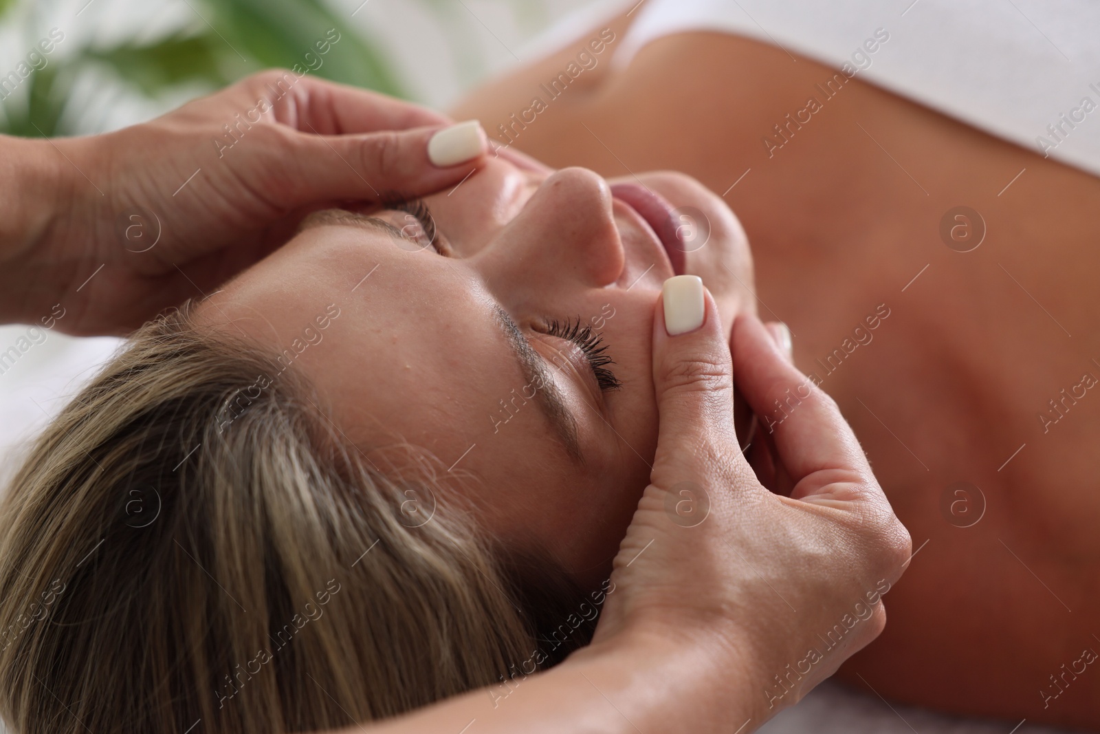 Beautiful woman receiving facial massage indoors, closeup Photo of Beautiful woman receiving facial massage indoors, closeup