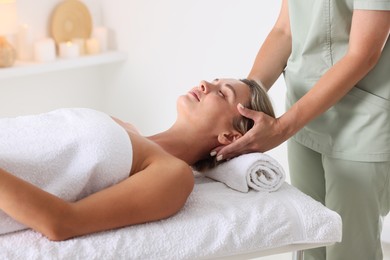 Photo of Beautiful woman receiving facial massage on couch indoors, closeup
