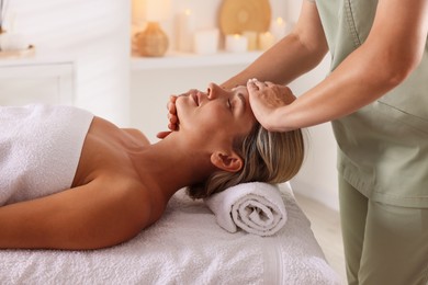 Photo of Beautiful woman receiving facial massage on couch in spa salon, closeup
