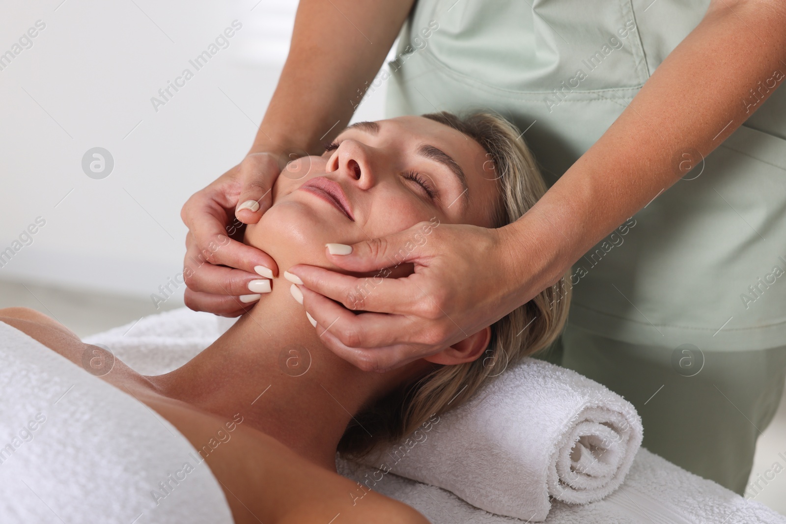 Beautiful woman receiving facial massage on couch in spa salon, closeup Photo of Beautiful woman receiving facial massage on couch in spa salon, closeup