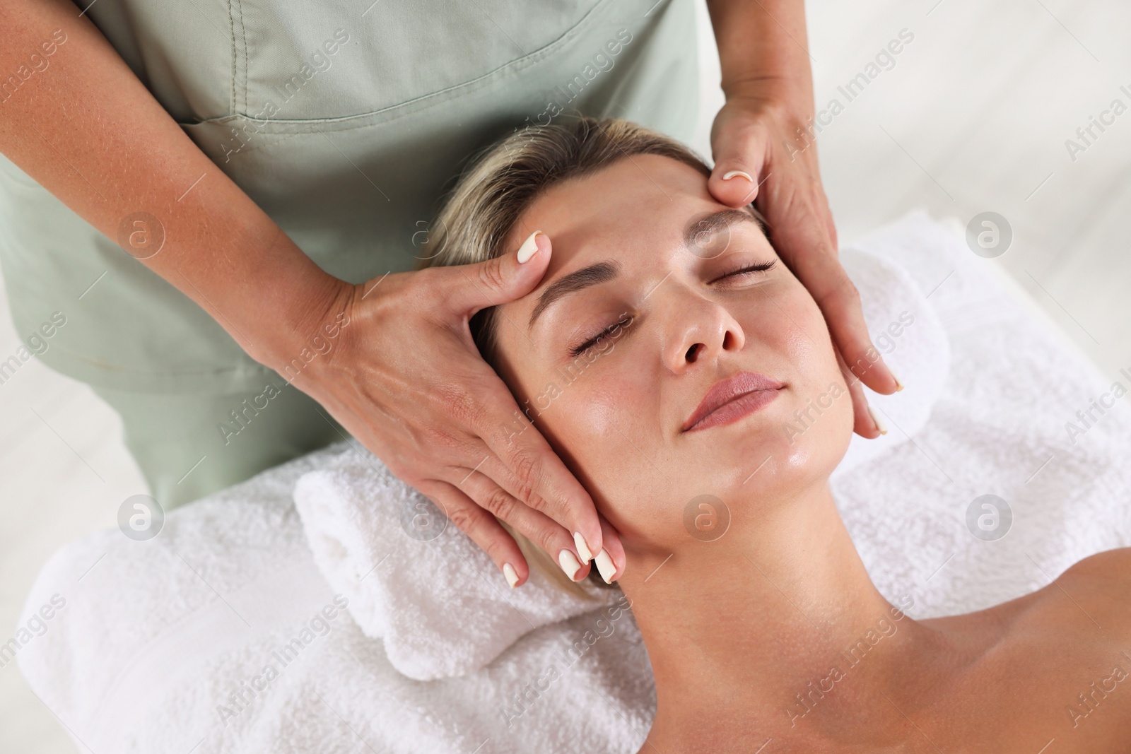 Beautiful woman receiving facial massage on couch indoors, closeup Photo of Beautiful woman receiving facial massage on couch indoors, closeup