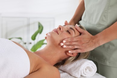 Photo of Beautiful woman receiving facial massage indoors, closeup