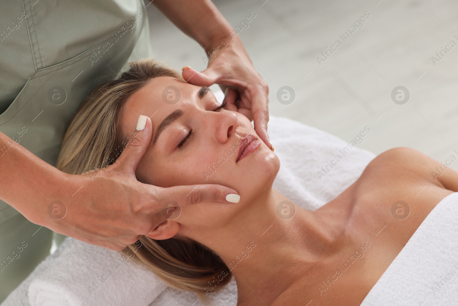 Beautiful woman receiving facial massage on couch indoors, closeup Photo of Beautiful woman receiving facial massage on couch indoors, closeup