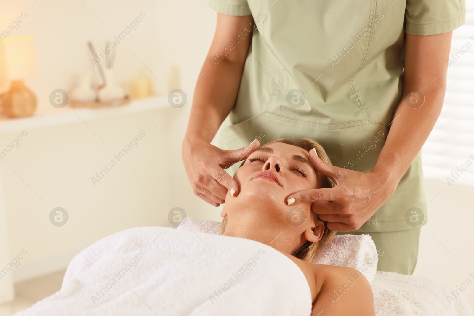 Beautiful woman receiving facial massage on couch indoors, closeup Photo of Beautiful woman receiving facial massage on couch indoors, closeup