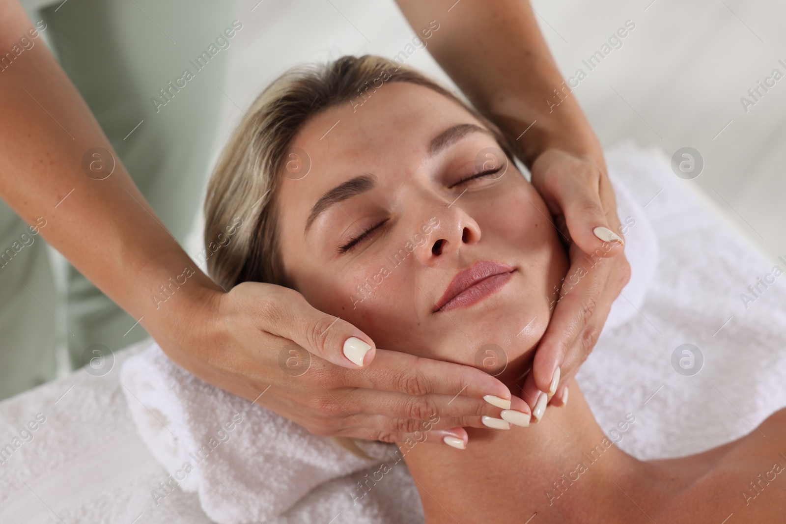 Beautiful woman receiving facial massage on couch indoors, closeup Photo of Beautiful woman receiving facial massage on couch indoors, closeup