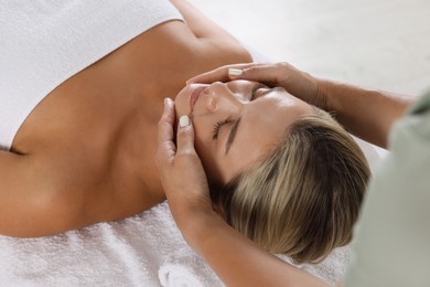 Photo of Beautiful woman receiving facial massage indoors, closeup