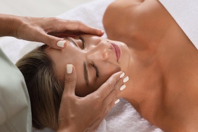 Photo of Beautiful woman receiving facial massage indoors, closeup