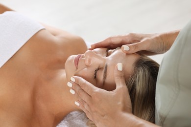 Photo of Beautiful woman receiving facial massage indoors, closeup