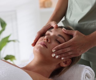 Photo of Beautiful woman receiving facial massage indoors, closeup