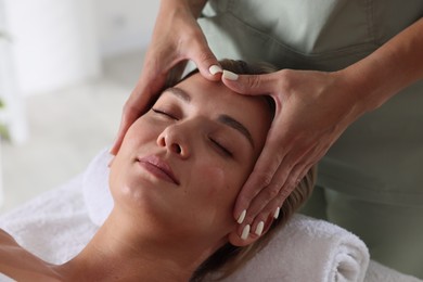 Photo of Beautiful woman receiving facial massage indoors, closeup