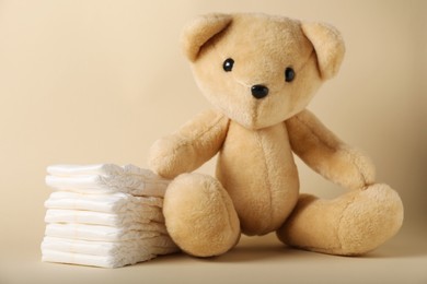 Photo of Toy bear and diapers on beige background. Baby accessories
