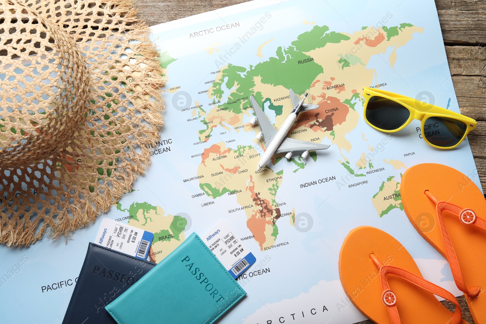 Photo of Time for summer vacation. World map, passports, flight tickets, toy plane and beach accessories on wooden table, flat lay