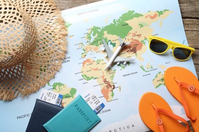 Photo of Time for summer vacation. World map, passports, flight tickets, toy plane and beach accessories on wooden table, flat lay
