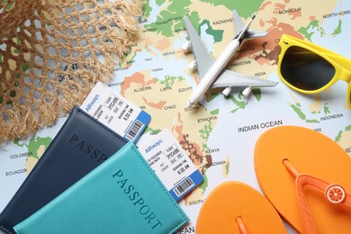Photo of Time for summer vacation. Passports, flight tickets, toy plane and beach accessories on world map, flat lay