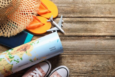 Photo of Time for summer vacation. World map, passports, toy plane, shoes and beach accessories on wooden table, flat lay. Space for text