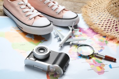 Photo of Time for summer vacation. World map, magnifying glass, toy plane, shoes, camera and straw hat on table, closeup
