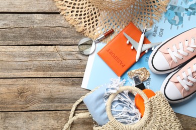 Photo of Time for summer vacation. World map, passport, toy plane, shoes, magnifying glass and beach accessories on wooden table, flat lay. Space for text