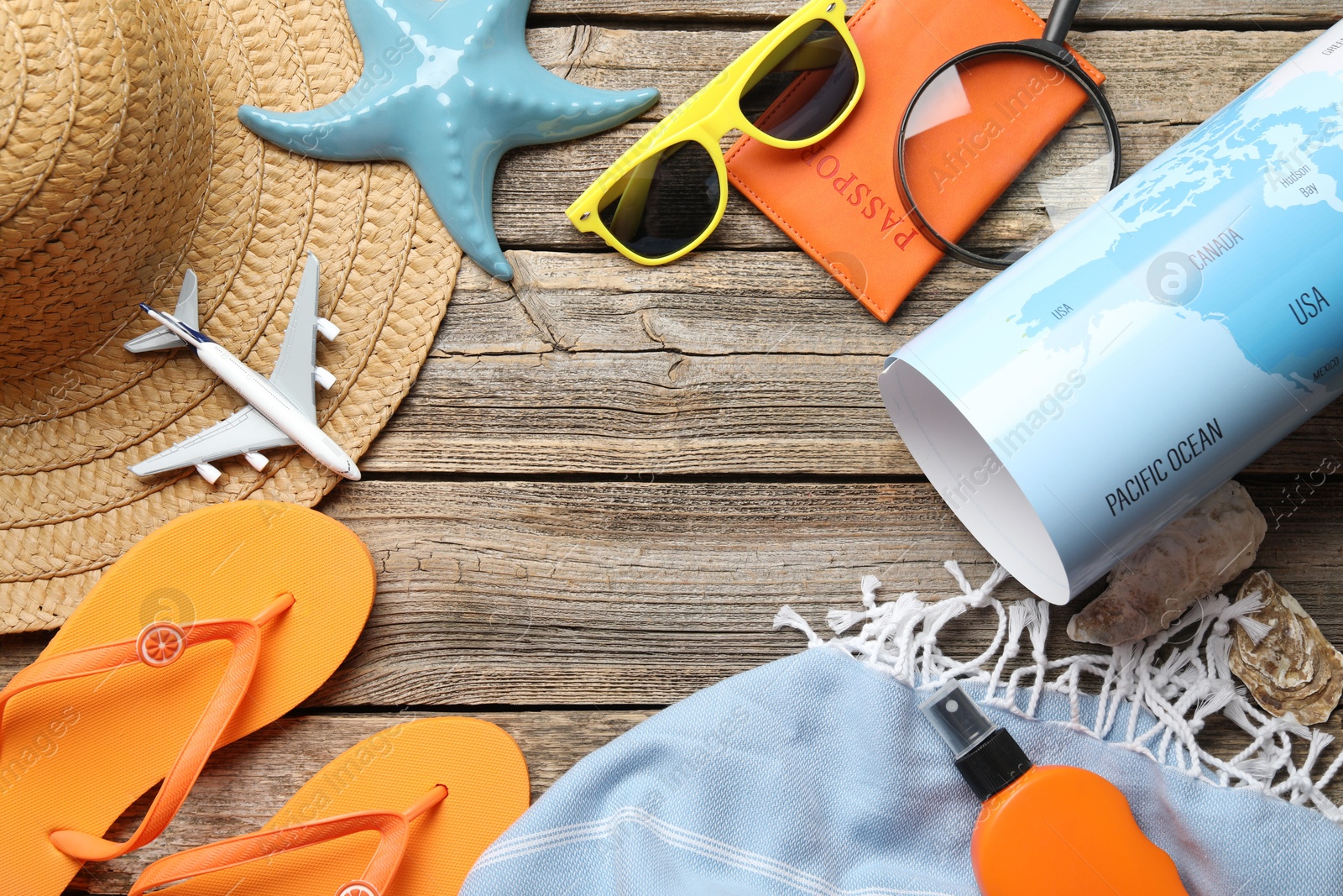 Photo of Time for summer vacation. World map, passport, toy plane and beach accessories on wooden table, flat lay. Space for text