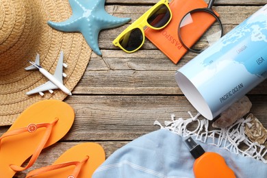 Photo of Time for summer vacation. World map, passport, toy plane and beach accessories on wooden table, flat lay. Space for text