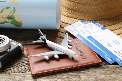 Photo of Time for summer vacation. World map, passport, flight tickets, toy plane, camera and straw hat on wooden table, closeup