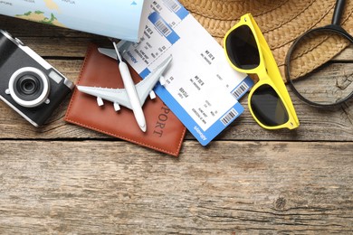 Photo of Time for summer vacation. World map, passport, flight tickets, toy plane, camera, magnifying glass and beach accessories on wooden table, flat lay. Space for text