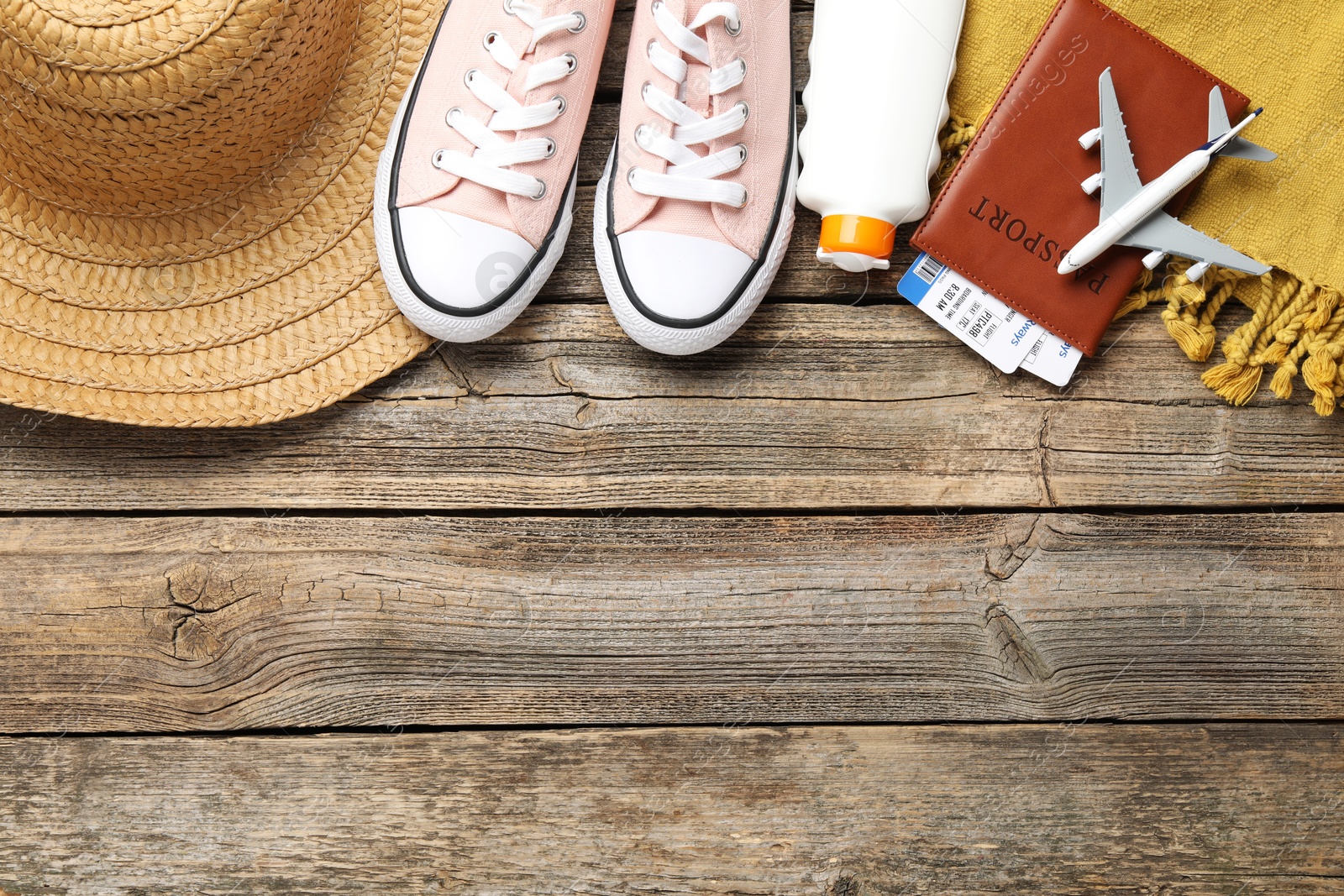 Photo of Time for summer vacation. Passport, flight tickets, toy plane, shoes and beach accessories on wooden table, flat lay. Space for text
