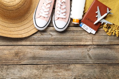 Photo of Time for summer vacation. Passport, flight tickets, toy plane, shoes and beach accessories on wooden table, flat lay. Space for text
