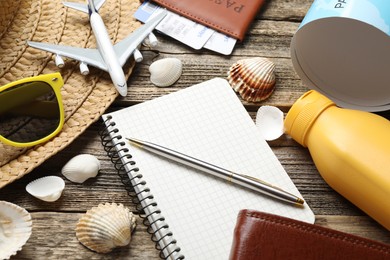 Photo of Time for summer vacation. Stationery, passport, flight tickets, toy plane, world map and beach accessories on wooden table, closeup