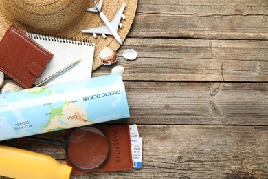 Photo of Time for summer vacation. Stationery, passport, flight tickets, toy plane, world map, purse and beach accessories on wooden table, flat lay. Space for text