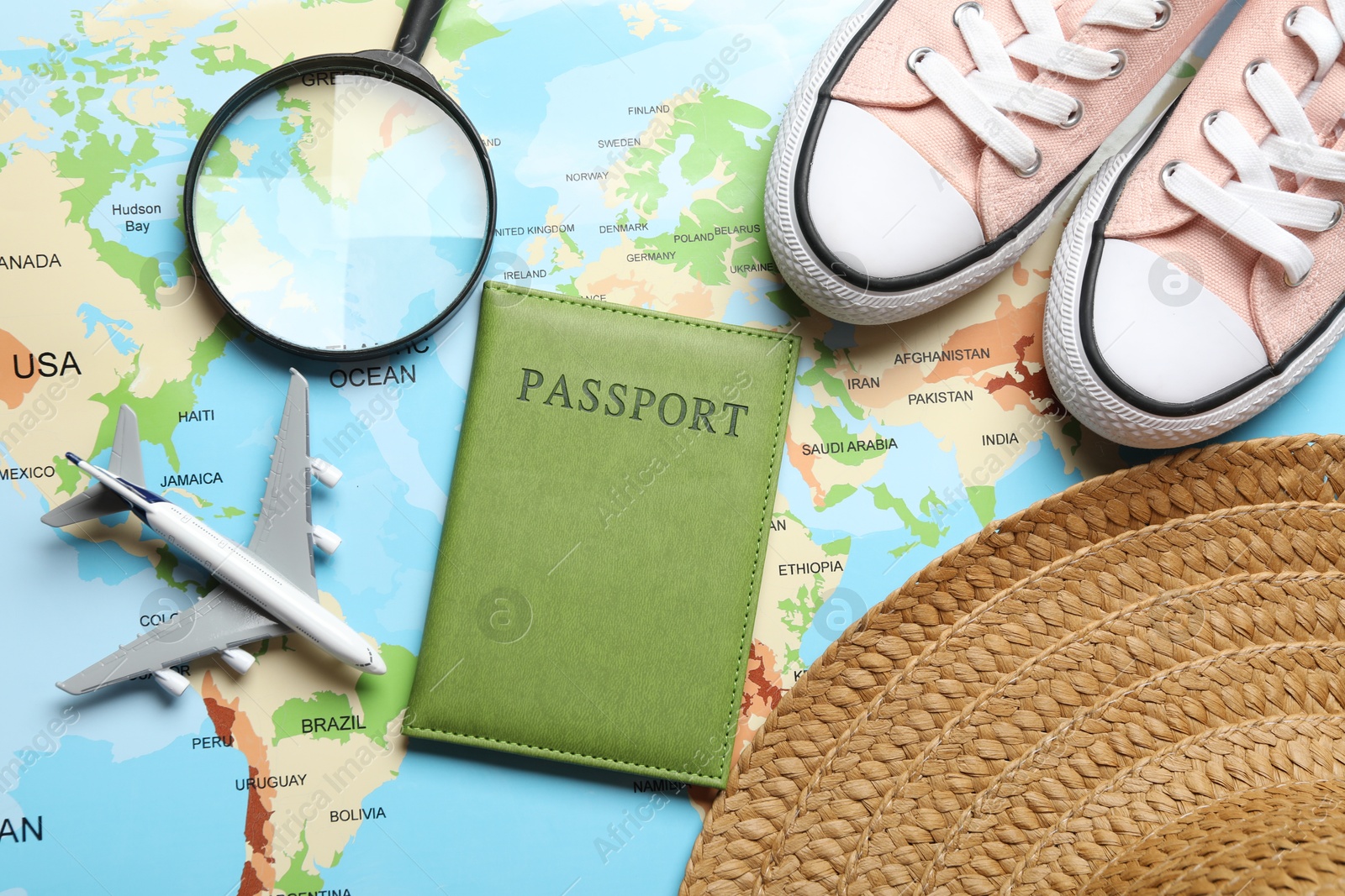 Photo of Time for summer vacation. Toy plane, passport, magnifying glass, shoes and straw hat on world map, flat lay