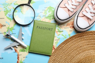 Photo of Time for summer vacation. Toy plane, passport, magnifying glass, shoes and straw hat on world map, flat lay