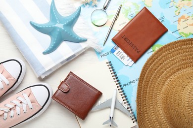 Photo of Time for summer vacation. World map, toy plane, passport, flight tickets, purse, shoes, notebook and beach accessories on light wooden table, flat lay