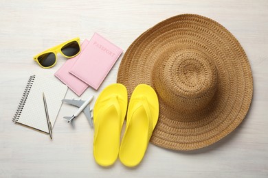 Photo of Time for summer vacation. Toy plane, passports, stationery and beach accessories on light wooden table, flat lay